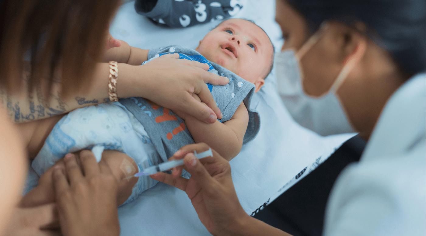 Duas pessoas vacinando um bebê